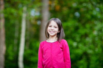 Fototapeta premium Portrait of cute school girl outside in blooming garden.