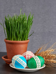 easter eggs in saucer and green wheat in the clay pot  on gray background