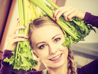 Woman in kitchen holds green celery