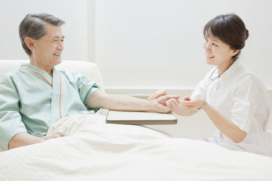 Nurse Checking Senior Man's Pulse