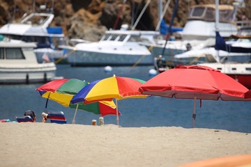 Three Colored Beach Umbrellas With Boats
