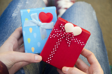 Blue and red gift boxes and hearts in woman hands