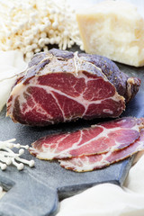 Homemade cured meat. Capocollo. Dried cured pork. Coppa sliced on pieces. Aged pork meat. Charcuterie.
