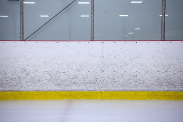 A straight on shot featuring well worn hockey boards in a recreational hockey rink.