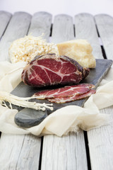 Homemade cured meat. Capocollo. Dried cured pork. Coppa sliced on pieces. Aged pork meat. Charcuterie.
