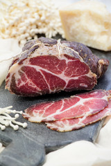 Homemade cured meat. Capocollo. Dried cured pork. Coppa sliced on pieces. Aged pork meat. Charcuterie.
