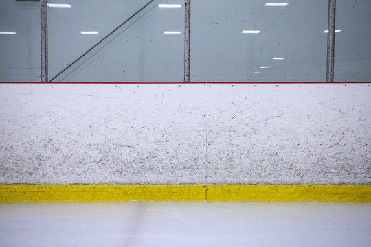 A straight on shot featuring well worn hockey boards in a recreational hockey rink.