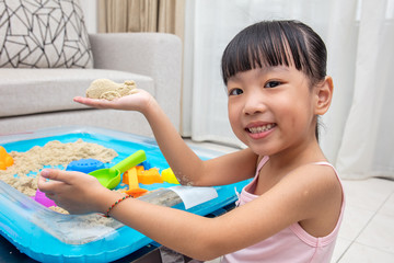 Happy Asian Chinese little girl playing kinetic sand at home