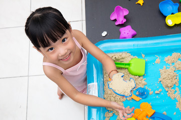 Happy Asian Chinese little girl playing kinetic sand at home