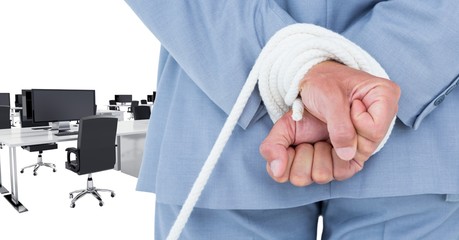 Mid section of businessman being tied up with rope in office