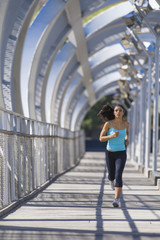 young beautiful athletic sport woman running and jogging crossing modern metal city bridge