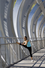 young beautiful athletic sport woman stretching after running crossing modern metal city bridge