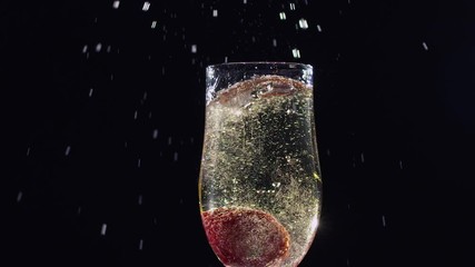 Mellow strawberry falling in glass with champagne wine. Slow motion - Powered by Adobe