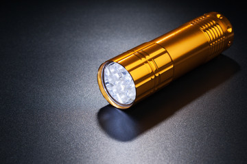 Golden flashlight on dark surface.