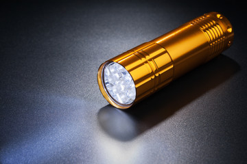 Luminous flashlight on dark surface.