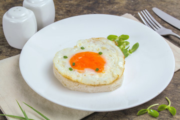 fried egg heart-shaped for breakfast on plate