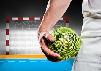 Close-up of male handball player holding ball against goal post