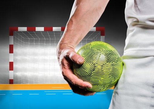 Close-up of male handball player holding ball against goal post