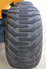 Obraz premium yellow tractor with a big wheel. Wheel with a large tread