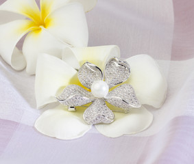 Fototapeta na wymiar Diamond and pearl brooch in flower shape on white flower background