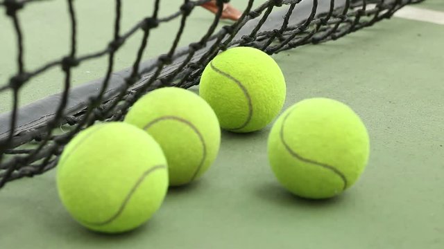 Sport of player touch rolling tennis ball on ground at green tennis court with racket	