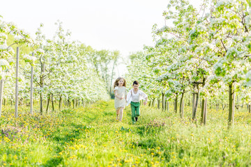  A boy and a girl are resting in a blooming garden in the spring