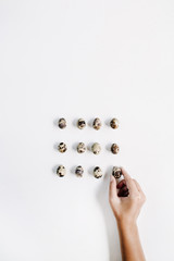 Female hand holding quail eggs on white background. Flat lay, top view. Easter concept.