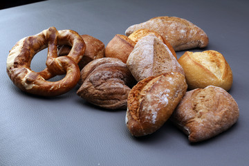 Different kinds of bread and bread rolls on board from above. Kitchen or bakery poster design.