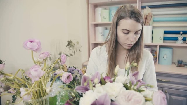 Florist at work: woman making bouquet of white roses and different flowers. Florist. Flower shop. Drawing up bouquets. The process of creating a floral composition. Flower composition.