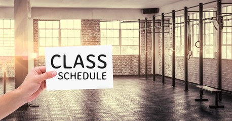 Hand holding placard with text class schedule in the gym