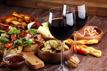 Italian antipasti wine snacks set. Cheese variety, Mediterranean olives, pickles, Prosciutto di Parma, tomatoes, artichokes and wine in glasses