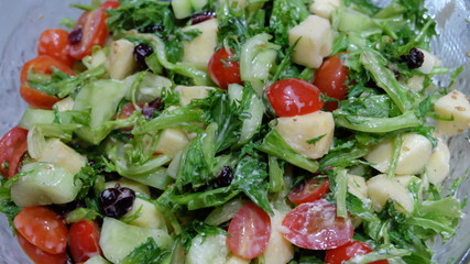 Salad with green leaves, tomatoes, cucumbers and apple