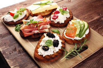 Bread Brushetta or authentic traditional spanish tapas set for lunch table. Sharing antipasti on party or summer picnic time over wooden rustic background.