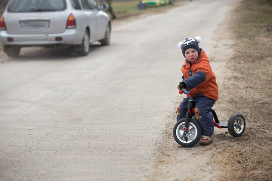 The Little Boy Is Riding A Tricycle