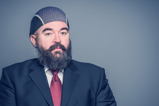 Adult bearded man in a suit and cap on a blue background