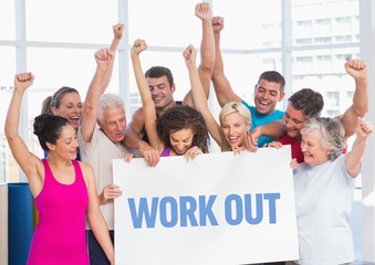 Fitness team standing with placard with work out text in gym