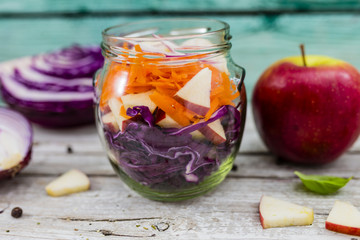 Red cabbage salad with fruits and vegetables in glass jar. Vegetarian food and healthy diet.
