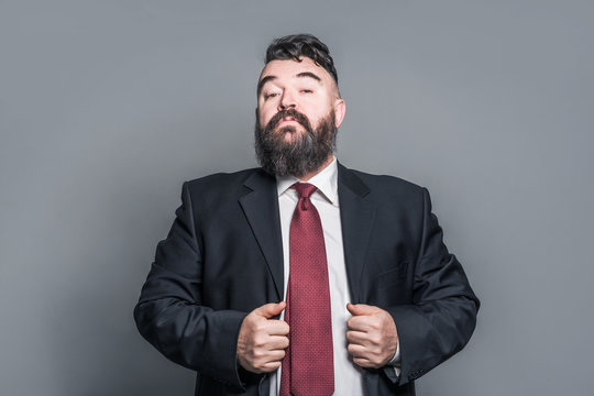 Adult bearded man in a suit and red tie on a gray background