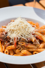 Penne pasta with bolognese sauce, parmesan cheese and basil