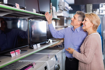 Mature couple buy in shop of household appliances TV
