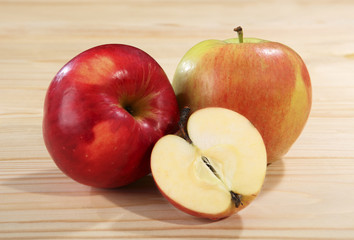 Two and a half ripe and juicy apples of red and green color on a wooden table. Close-up.
