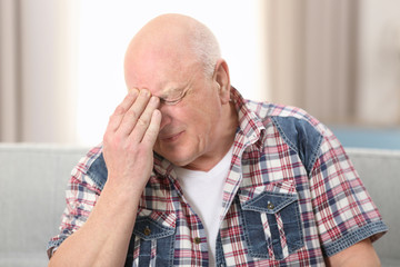 Obraz premium Senior man suffering from headache at home