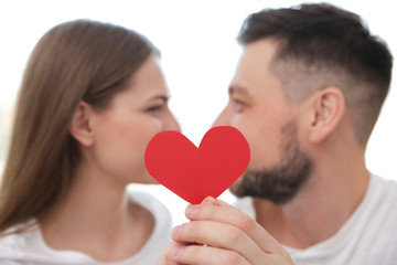 Happy young couple with red paper heart on white background