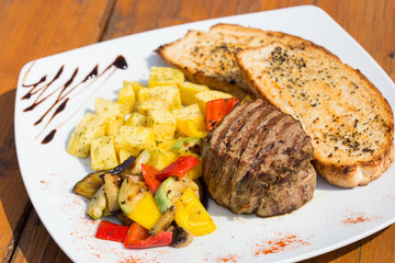 Close up Gourmet Appetizing Roasted Beef Steak with Potato Wedges and Other Vegetables