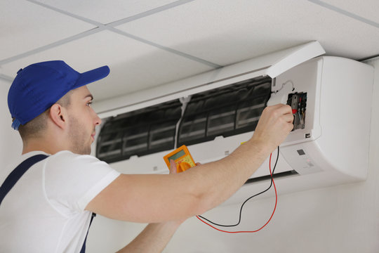 Electrician measuring voltage in air conditioner