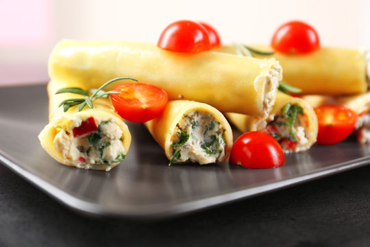 Delicious stuffed cannelloni with cherry tomatoes on rectangular plate