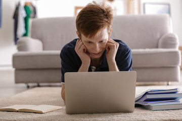 Teenager working with laptop while doing lessons at home