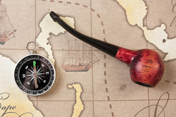 tobacco pipe and compass on map