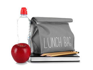 Lunch bag, bottle of water, apple and stationery on white background