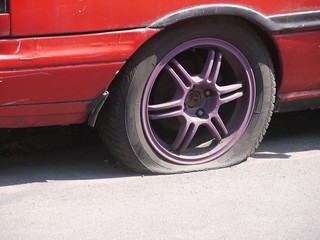 Obraz na płótnie Canvas Dirty old red car tire break deflated